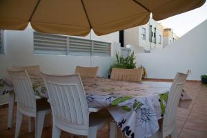 mesa de comedor con sillas y sombrilla en Acogedor adosado muy cerca de la playa en Almazora