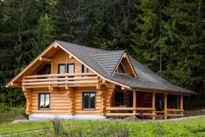 uma cabana de madeira com um telhado preto em Harghita Log Houses em Izvoare
