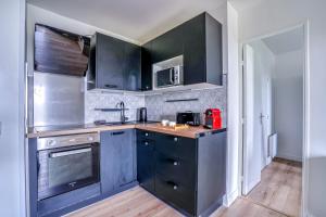 a kitchen with black cabinets and stainless steel appliances at Le Convertible - Proche Disney - Parking Privé in Chalifert