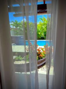 a window with a view of a yard with flowers at Pousada Fasani in Ilha de Boipeba