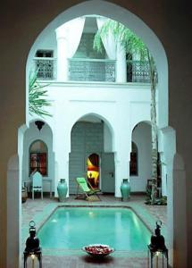 a swimming pool in a house with an archway at Riad Herougui in Marrakesh
