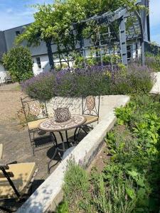 Drömhus på Österlen في Glemminge: طاولة وكراسي في حديقة بها زهور أرجوانية
