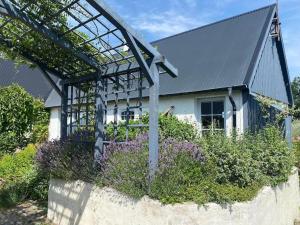 een huis met een pergola en paarse bloemen bij Drömhus på Österlen in Glemminge