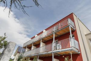 - un bâtiment rouge avec des balcons et des panneaux solaires dans l'établissement Hotel Schönau, à Lindau