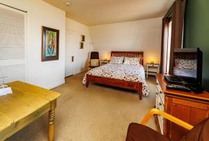 a bedroom with a bed and a desk and a television at Auberge La Marmite in La Malbaie