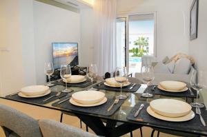 a dining room with a table with plates and wine glasses at Premium Ferienwohnung: Allegra - Alba - Residential in Ciudad Quesada