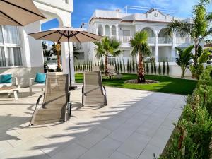 a patio with chairs and an umbrella in front of a house at Premium Ferienwohnung: Allegra - Alba - Residential in Ciudad Quesada