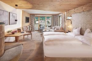 Habitación de hotel con 2 camas y sala de estar. en Das Karwendel - Ihr Wellness Zuhause am Achensee, en Pertisau