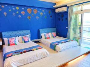 two beds in a room with blue walls at 愛海居民宿Love in Taitung City