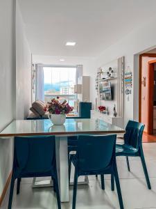 a dining room with a glass table and blue chairs at Estada inesquecível 09 Bacutia/Guarapari Premium in Guarapari +51 photos