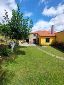 une maison jaune avec un arbre dans la cour dans l'établissement Casas de Maragouzos, à Silleda