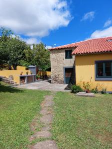 une maison avec une cour herbeuse à côté d'un bâtiment dans l'établissement Casas de Maragouzos, à Silleda