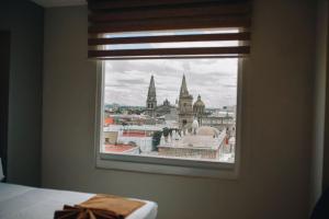 a view of a city from a bedroom window at Hotel Dali Plaza Ejecutivo in Guadalajara
