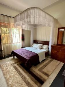 a bedroom with a canopy bed and a rug at Makanga Hill Suites in Kabale