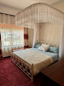 a bedroom with a canopy bed and a window at Makanga Hill Suites in Kabale
