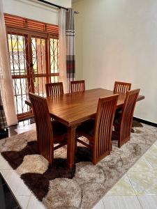 una mesa de comedor de madera con 4 sillas sobre una alfombra en Makanga Hill Suites, en Kabale