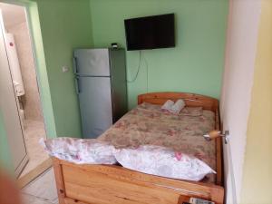 - une chambre avec un lit, un réfrigérateur et une télévision dans l'établissement Квартири - стаи за гости, Ахтопол, à Ahtopol