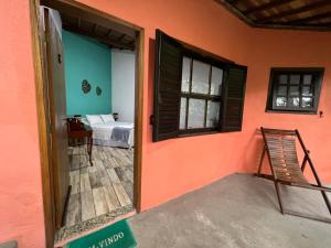 a room with an open door with a bed and a chair at Pousada Pé da Mata Maresias in Maresias