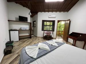 a bedroom with a large bed and a piano at Pousada Pé da Mata Maresias in Maresias