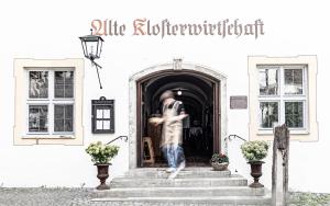 een standbeeld van een man die uit een deur loopt bij Klosterwirt Polling in Polling