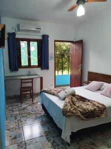 1 dormitorio con 2 camas, escritorio y ventana en Pousada Retiro das Caravelas, en Cananéia