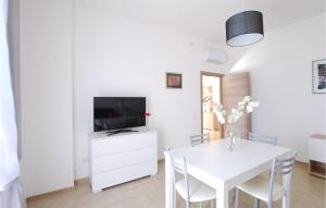 een witte eetkamer met een witte tafel en een tv bij 2 Bedroom Beautiful Home In Corridonia in Corridonia