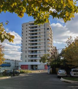 un edificio blanco alto con coches estacionados en un estacionamiento en Sunset Bucharest 84, en Bucarest