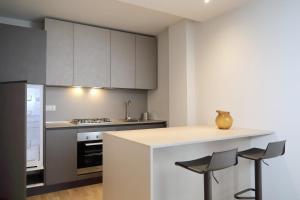 a kitchen with white cabinets and a counter with stools at Residenza Cristoforo in Udine