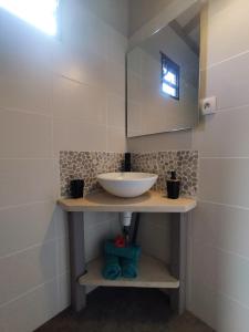 uma casa de banho com um lavatório e um espelho em Coco et Cajou Bungalows em Sainte-Anne