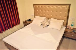 a bedroom with a large bed with white sheets and pillows at Hotel Visau,Shirdi in Shirdi