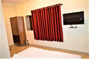 a room with a red curtain and a tv at Hotel Visau,Shirdi in Shirdi