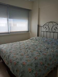 a bedroom with a bed with a floral bedspread and two windows at Radar Mirador Cabo Corrientes in Mar del Plata