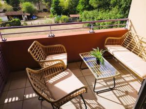 3 sillas de mimbre y una mesa en el balcón en Casteljaloux Appartement 2 chambres balcon parking résidence calme, en Casteljaloux