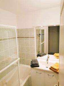 y baño con bañera, lavamanos y ducha. en Casteljaloux Appartement 2 chambres balcon parking résidence calme, en Casteljaloux