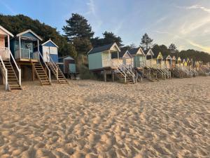 uma fileira de cabanas de praia numa praia arenosa em Crab Cottage em Wells-next-the-Sea