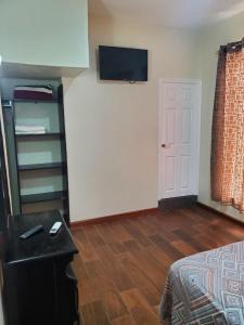 サンタ・クルス・ウアトゥルコにあるDepartamento ELSA. La Crucecita, Huatulco.の壁にテレビとベッドが備わる客室です。