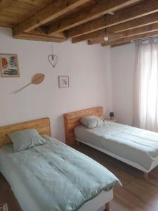 Roquetaillade的住宿－Gîte chaleureux au cœur du village，一间卧室设有两张床和窗户。