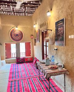 a living room with a table and a rug at Alqalah Inn in Al Ḩamrāʼ