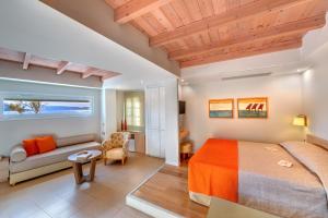a hotel room with a bed, couch, table and chairs at Nissaki Beach Hotel in Naxos Chora