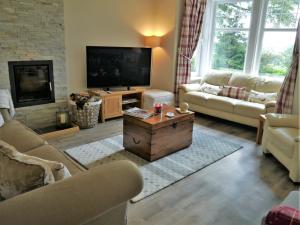 a living room with a couch and a tv at Glaisters Farmhouse in Castle Douglas