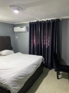 1 dormitorio con 1 cama y una ventana con cortinas en Oak Suites & Bar, en Benin City