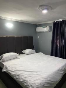 Bett mit weißer Bettwäsche und Kissen in einem Zimmer in der Unterkunft Oak Suites & Bar in Benin-Stadt