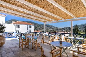 un patio con mesas y sillas y vistas. en Aperitton Hotel en Skopelos Town