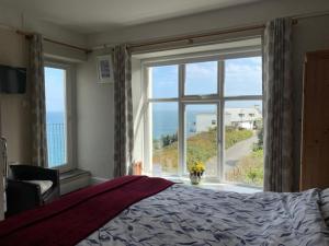 a bedroom with a bed and a large window at Honeycombe House in Mevagissey