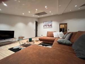 Gîte Chez Doumé في هوفاليز: غرفة معيشة مع أريكة وتلفزيون بشاشة مسطحة