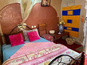 a bedroom with a bed with pink sheets and a table at Guesthouse Panorama Todra in Tinerhir