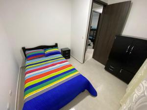 1 dormitorio con 1 cama con una manta a rayas de colores en Hospedaje Santa Rosa de Cabal - Apartamento, en Santa Rosa de Cabal