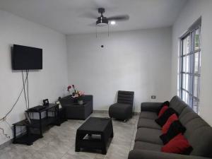 uma sala de estar com um sofá e uma televisão em CASA DYA em Cozumel