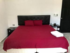 um quarto com uma cama vermelha e 2 almofadas vermelhas em CASA DYA em Cozumel