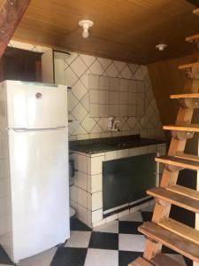 a kitchen with a white refrigerator and a checkered floor at Chale da pesca in Arraial do Cabo